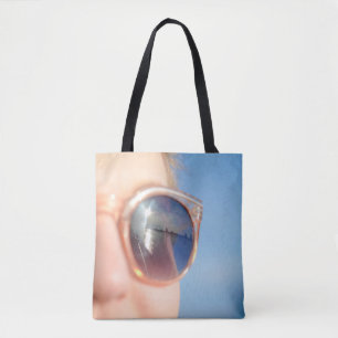 Woman wearing brown framed sunglasses tote bag