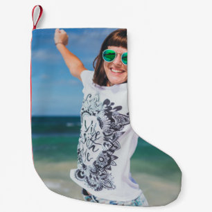 Woman wearing white and black shirt jumping near s small christmas stocking