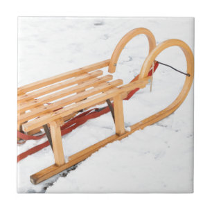 Wooden children sled in winter snow tile