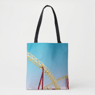 Yellow and red roller coaster under blue sky at da tote bag