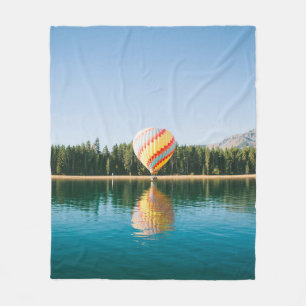 Yellow, red, and blue hot air balloon near trees a fleece blanket