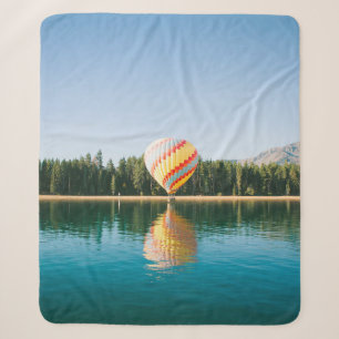 Yellow, red, and blue hot air balloon near trees a sherpa blanket