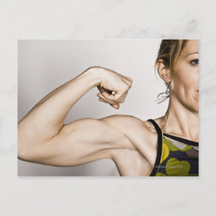 Young blonde female flexes bicep muscle while postcard