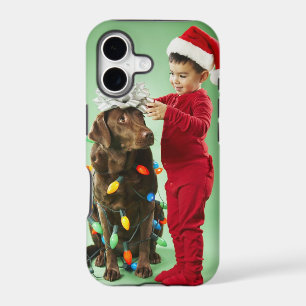 Young boy wrapping Christmas lights around a dog