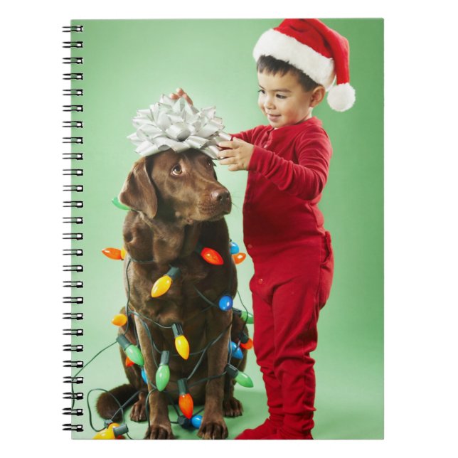Young boy wrapping Christmas lights around a dog Notebook (Front)
