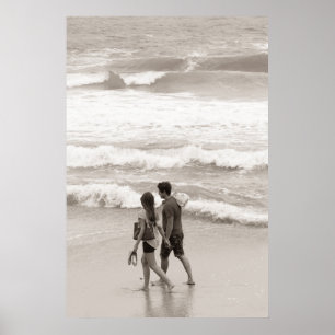 Young couple walking on the beach poster