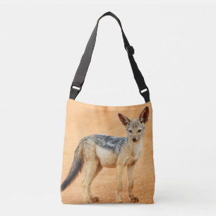 Young jackal standing on red sand, Serengeti Crossbody Bag