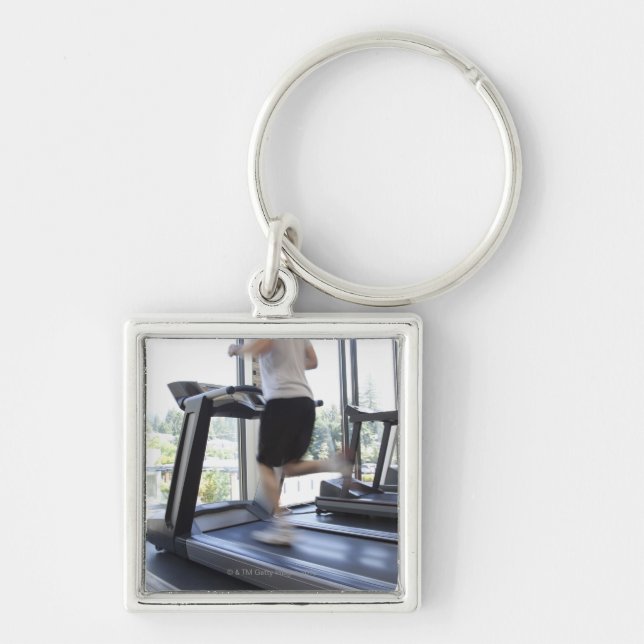 Young man running on a treadmill at health club, key ring (Front)