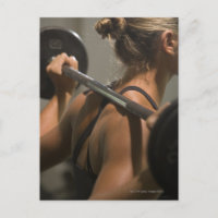 Young woman exercising with barbell, rear view