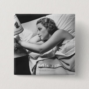 Young woman lying on bed turning off lamp on 15 cm square badge