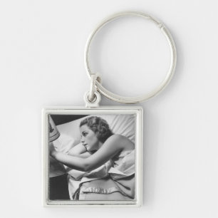 Young woman lying on bed turning off lamp on key ring